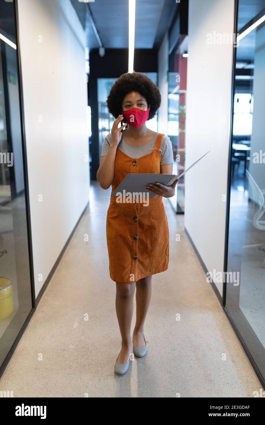 Gemischte Rasse Geschäftsfrau trägt Gesichtsmaske in kreativen Büro Stockfoto