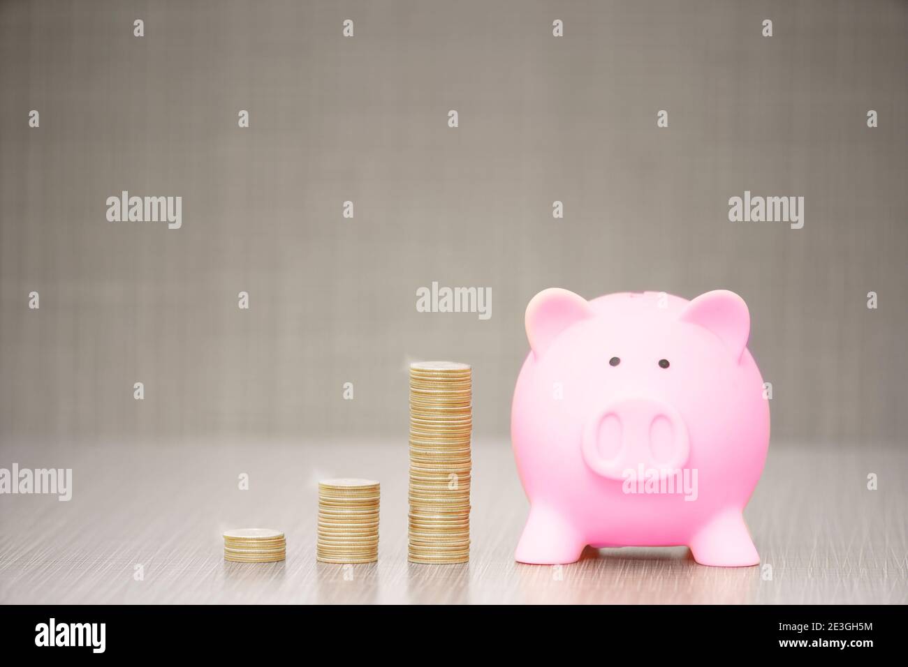 Pink Piggy Bank mit Münzen auf grauem Hintergrund. Mit Kopierraum.Einsparendes Anlagekonzept Stockfoto