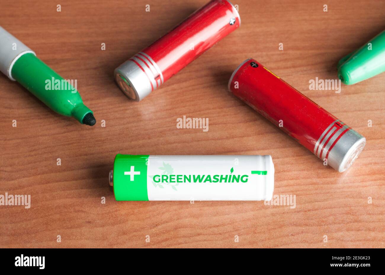 Greenwashing-Konzept: Einige Batterien und ein grüner Marker auf einem Holztisch. Greenwashing ist eine Kommunikationstechnik, die darauf abzielt, ein falsches Bild zu erstellen Stockfoto