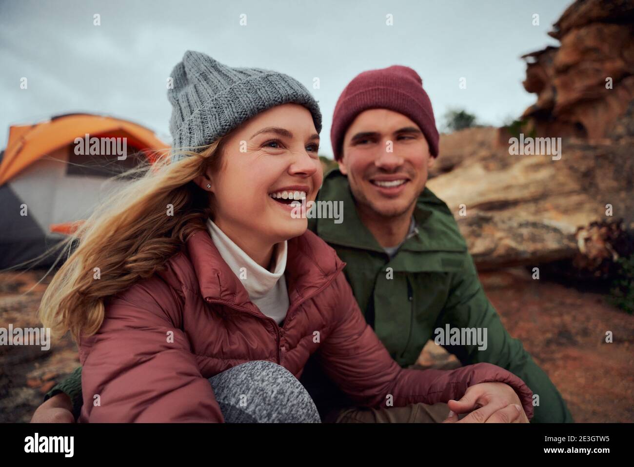 Glückliches junges Paar entspannend während Camping sitzen außerhalb Zelt suchen Im Winter weg Stockfoto