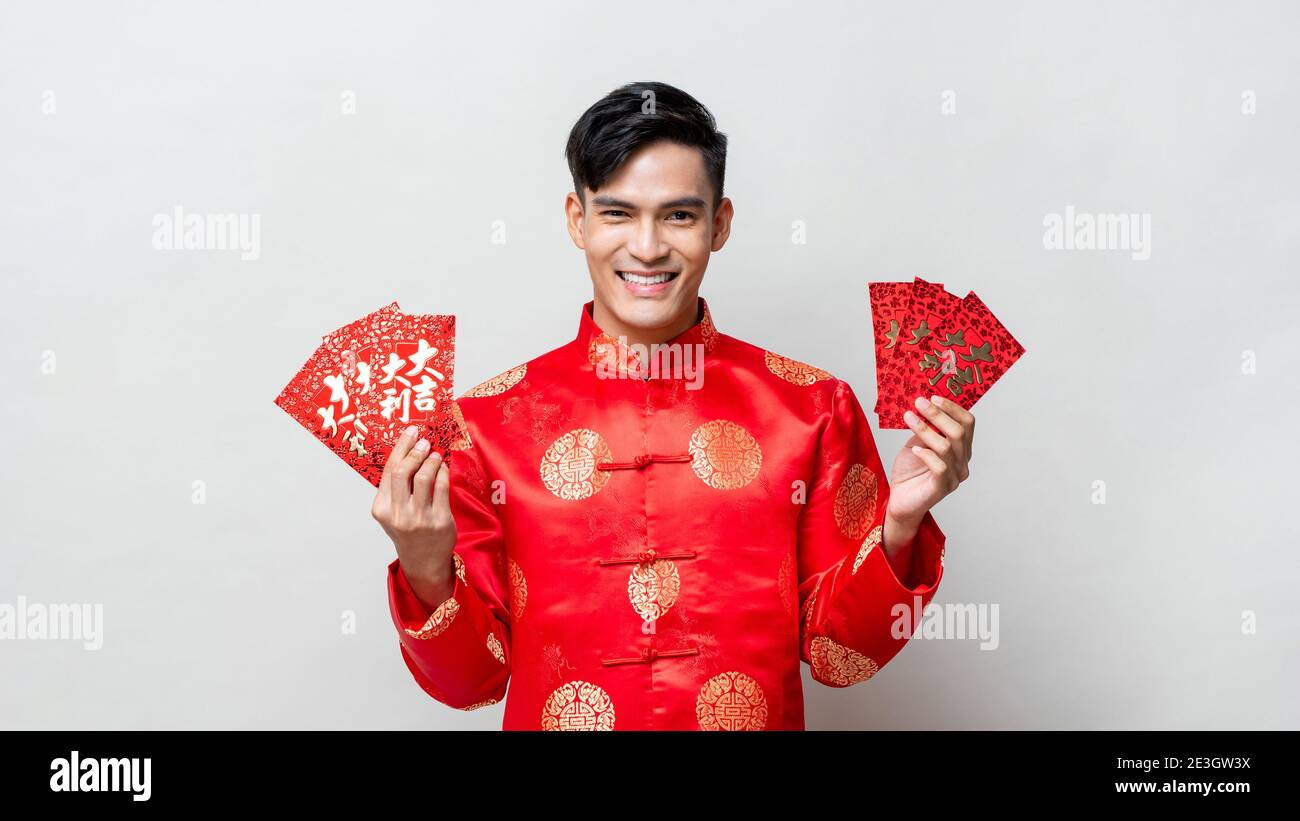 Lächelnder glücklicher asiatischer Mann in traditioneller orientalischer Tracht mit roten Umschlägen oder Ang POA mit Text bedeutet großes Glück, großen Gewinn, isoliert auf Licht Stockfoto
