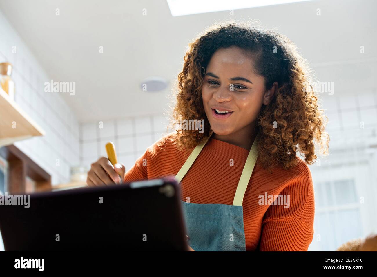 Glückliche junge afroamerikanische Frau mit Videoanruf beim Kochen In der Küche zu Hause Stockfoto