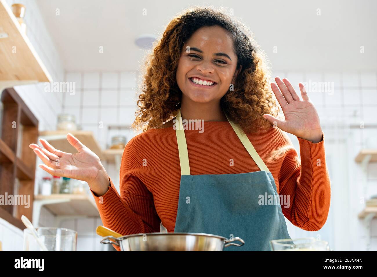 Junge glückliche afroamerikanische Frau winkt die Hände zur Kamera, während Videoanruf in der Küche zu Hause Stockfoto