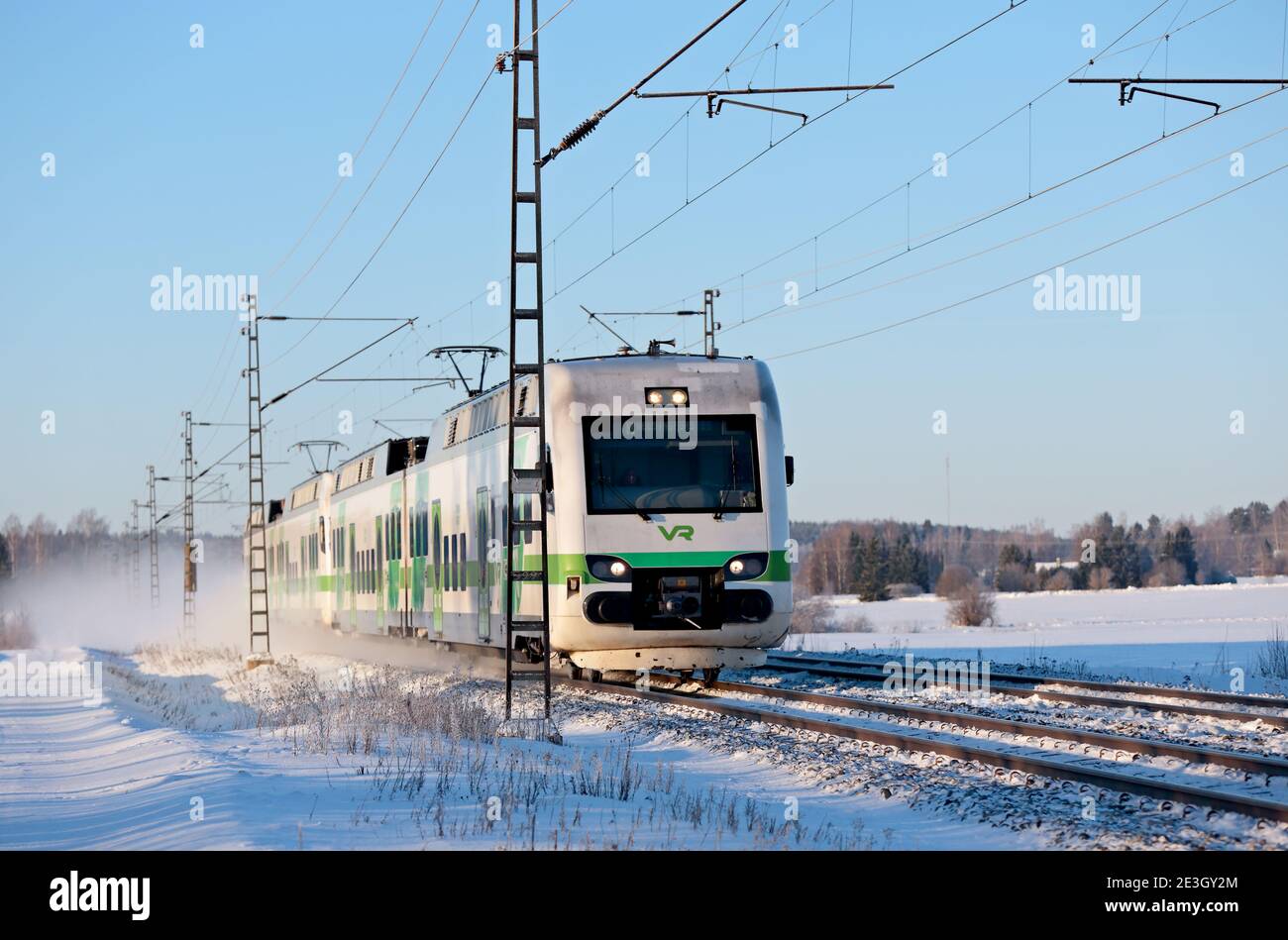 Hameenlinna Finland 01/17/2021 Grüne und weiße Personenbahn im Schnee Staub, der vorbeikommt Stockfoto