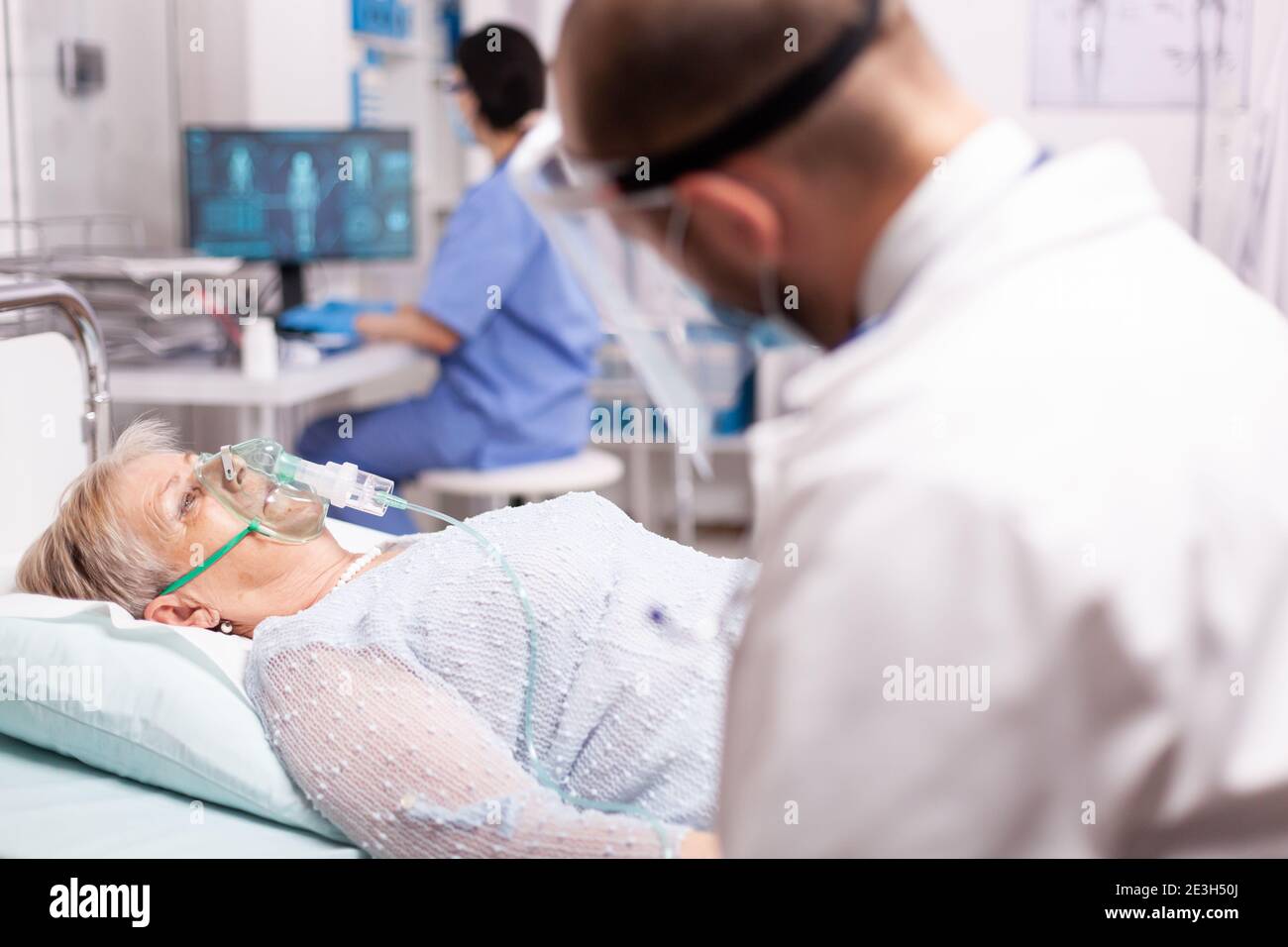 Arzt überprüft ältere Frau mit Sauerstoffmaske Atmung stark wegen der Infektion mit covid19. Patient im Krankenhauszimmer, der während einer Coronavirus-Pandemie auf einem medizinischen Bett mit infizierter Lunge liegt und ein Atemproblem hat. Stockfoto
