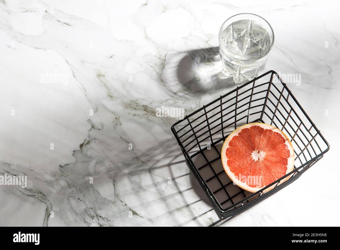 Sommer Schreibwaren Stillleben Szene. Nahaufnahme von geschnittenen Grapefruitfrüchten auf weißem Tischhintergrund im Sonnenlicht. Leere Papierkarten, Einladungen Mockup Szene Stockfoto