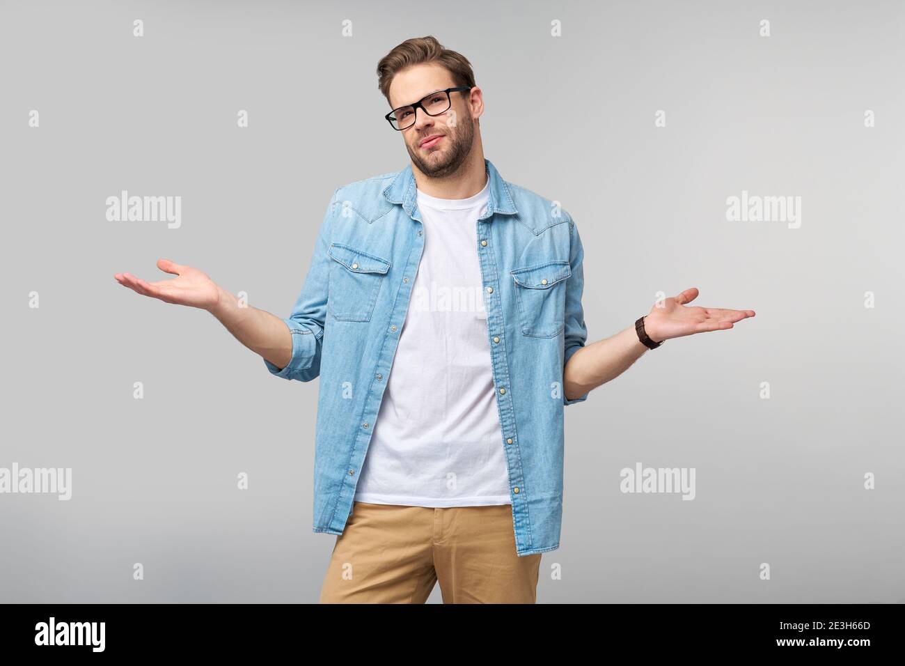 Porträt von verwirrt ahnungslos jungen Mann in Jeans Hemd stehend Auf grauem Hintergrund Stockfoto