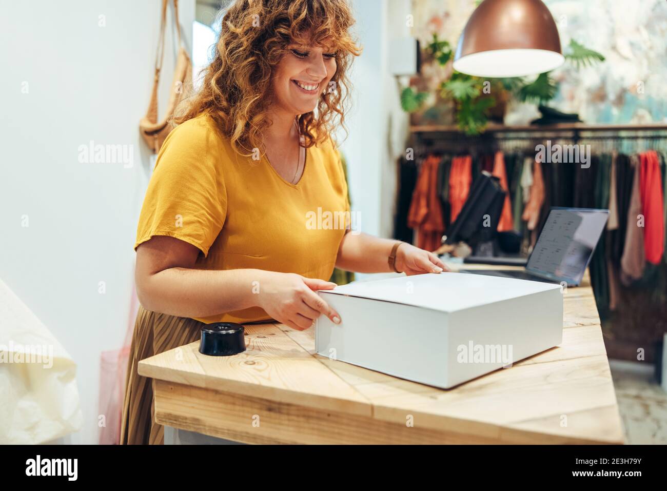 Frau bereitet ein Paket für die Lieferung für eine Online-Bestellung vor. Frau läuft Online-Shop aus ihrer Mode-Boutique. Stockfoto