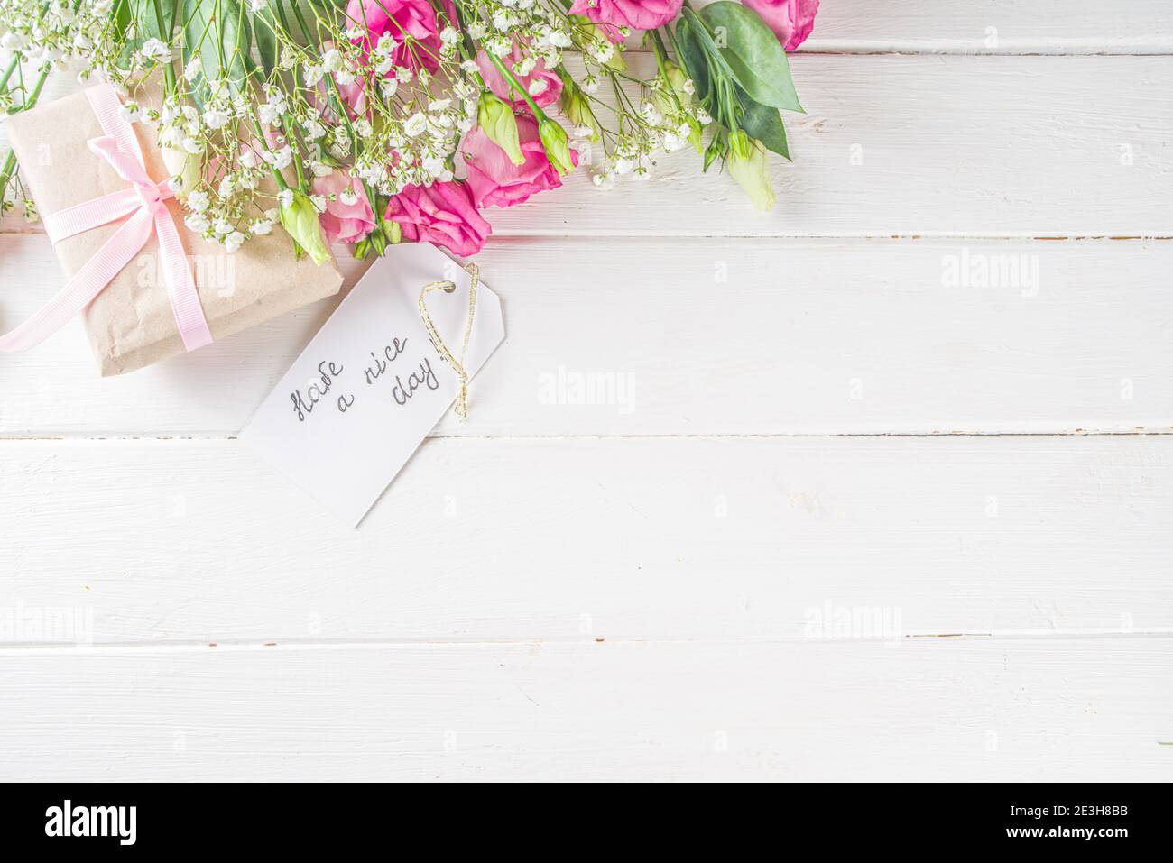 Blumenstrauß aus Frühling, Sommerblumen, Kaffeetasse und Noten Guten Morgen, haben Sie einen schönen Tag auf weißem Holztisch. Sommer Morgen schönes Frühstück, begrüßen Stockfoto