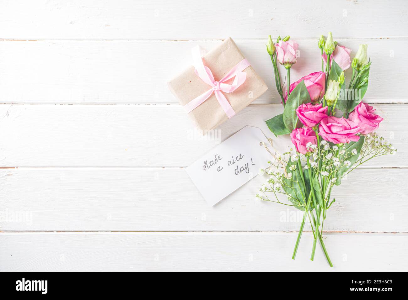 Blumenstrauß aus Frühling, Sommerblumen, Kaffeetasse und Noten Guten Morgen, haben Sie einen schönen Tag auf weißem Holztisch. Sommer Morgen schönes Frühstück, begrüßen Stockfoto