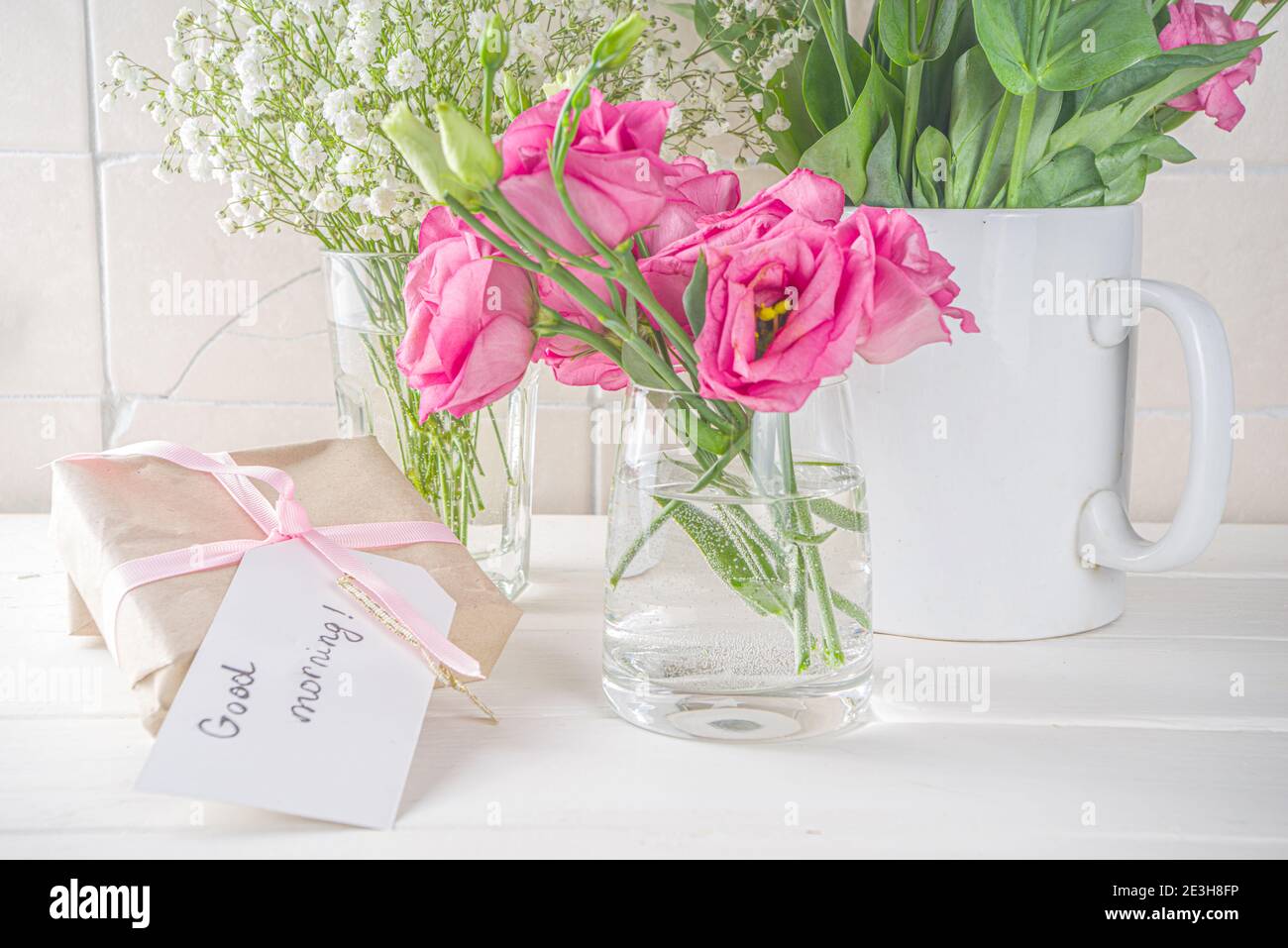 Blumenstrauß aus Frühling, Sommerblumen, Kaffeetasse und Noten Guten Morgen, haben Sie einen schönen Tag auf weißem Holztisch. Sommer Morgen schönes Frühstück, begrüßen Stockfoto