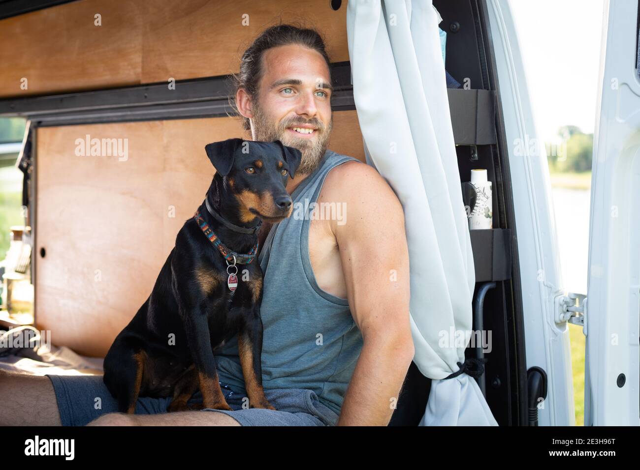 Der Mann und sein Hund schauen aus einem Wohnmobil Stockfoto