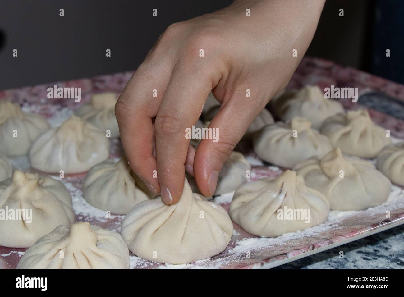 Georgische Knödel khinkali mit Fleisch. Die Hand hält den Khinkali am Schwanz. Stockfoto