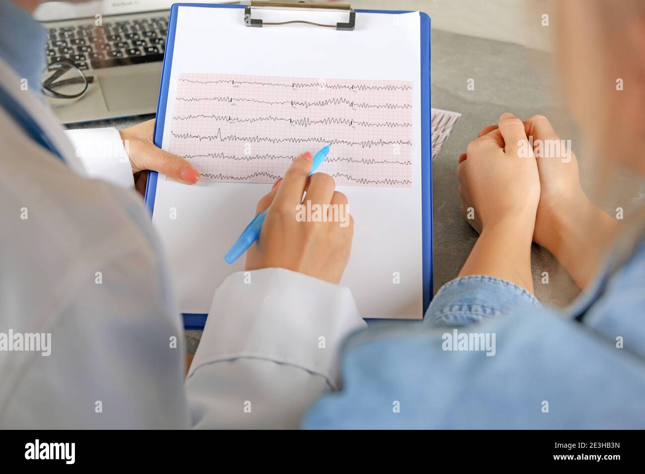 Ärztin, die die Ergebnisse des Elektrokardiogramms mit dem Patienten überprüft Stockfoto
