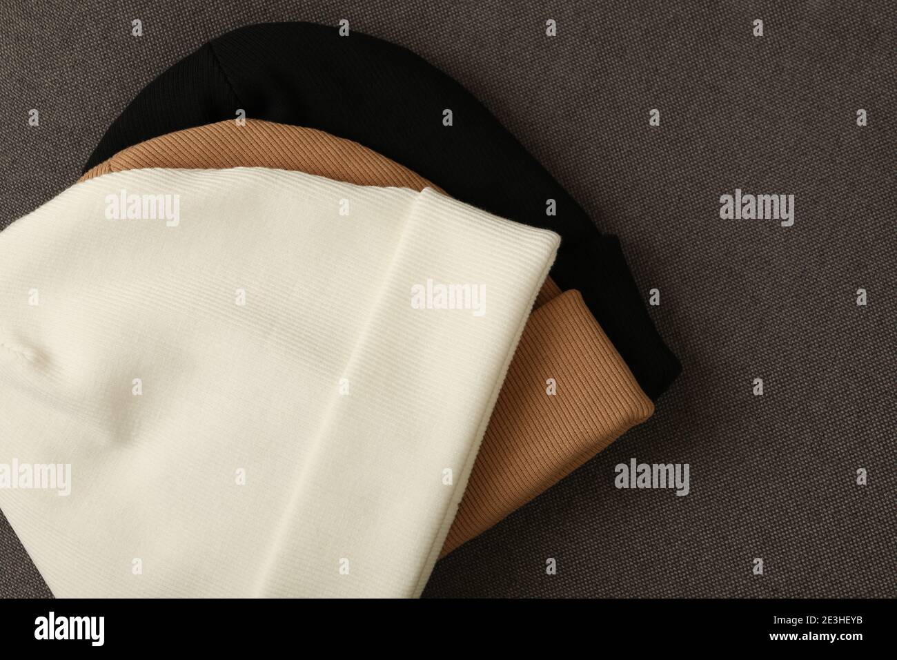 Drei stilvolle Beanies auf Stoffhintergrund, Nahaufnahme Stockfoto