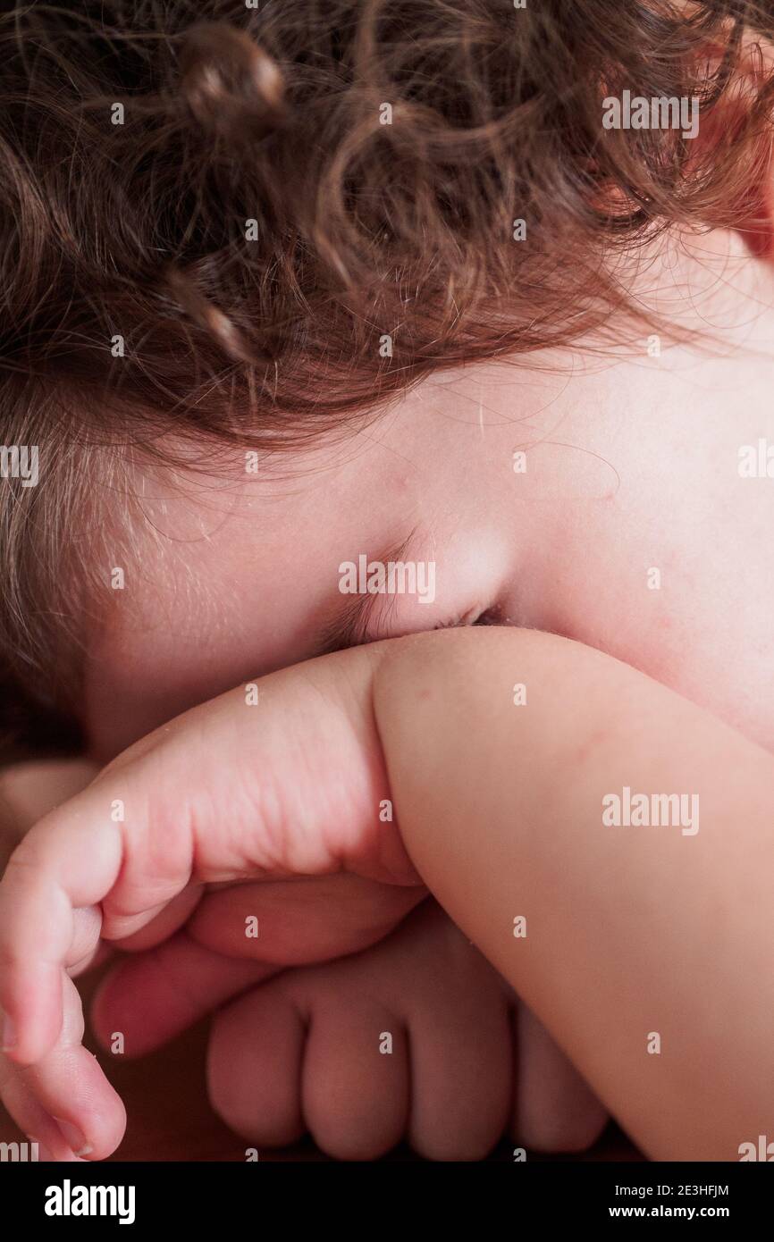 Ein verhaschtes Kleinkind versteckt ihr Gesicht hinter ihrer Hand Stockfoto