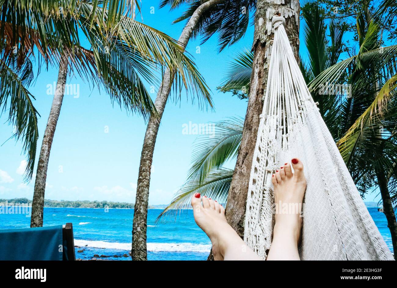 Frau, die sich in einer Hängematte am Strand auf einem entspannt karibische Insel umgeben von Palmen Stockfoto