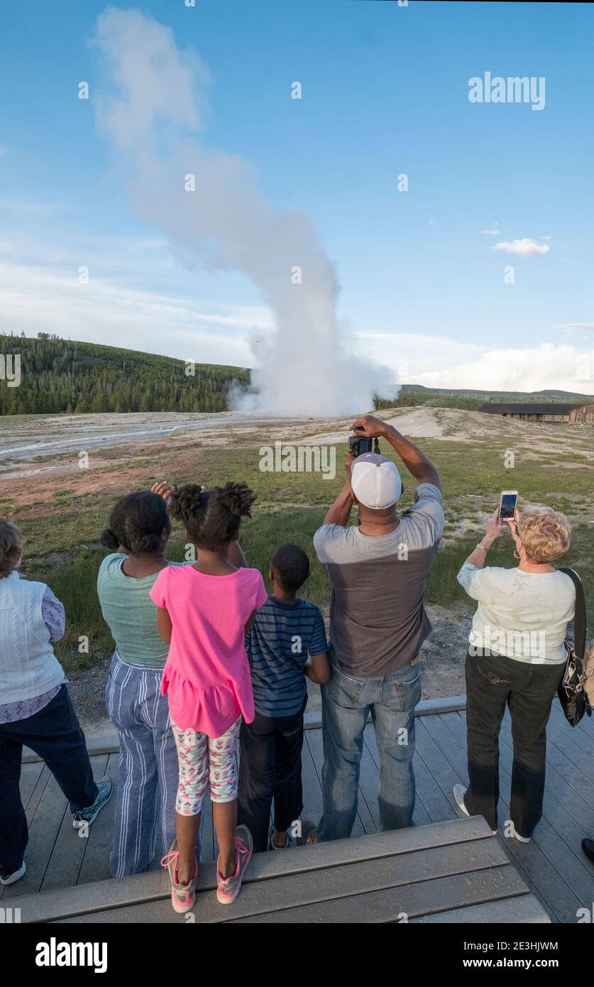 Besucher beobachten den Ausbruch des Old Faithful Geysir im Yellowstone Nationalpark, Wyoming, USA. Stockfoto