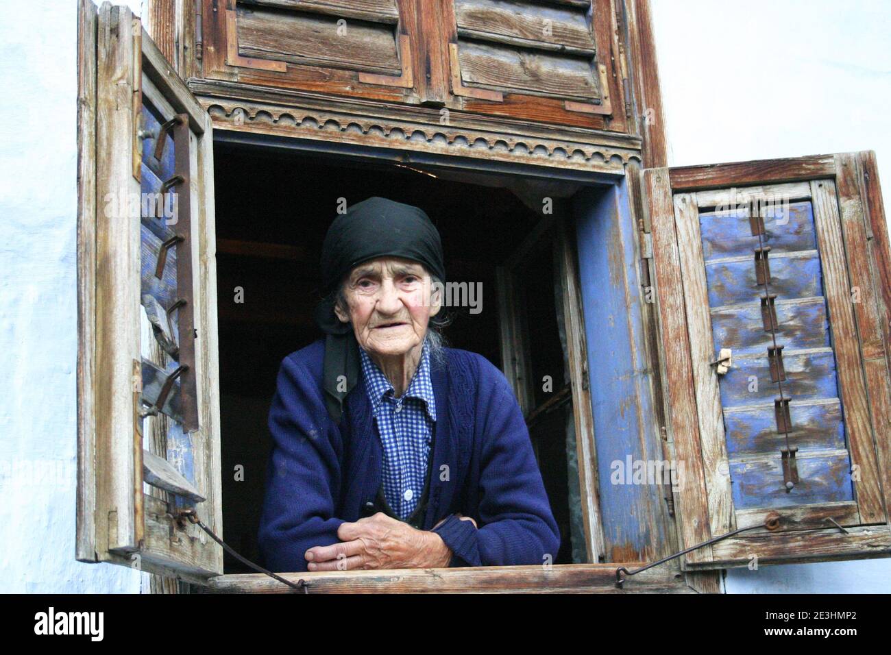 Brasov County, Rumänien. Ältere Frau, die aus dem Fenster schaut. Stockfoto