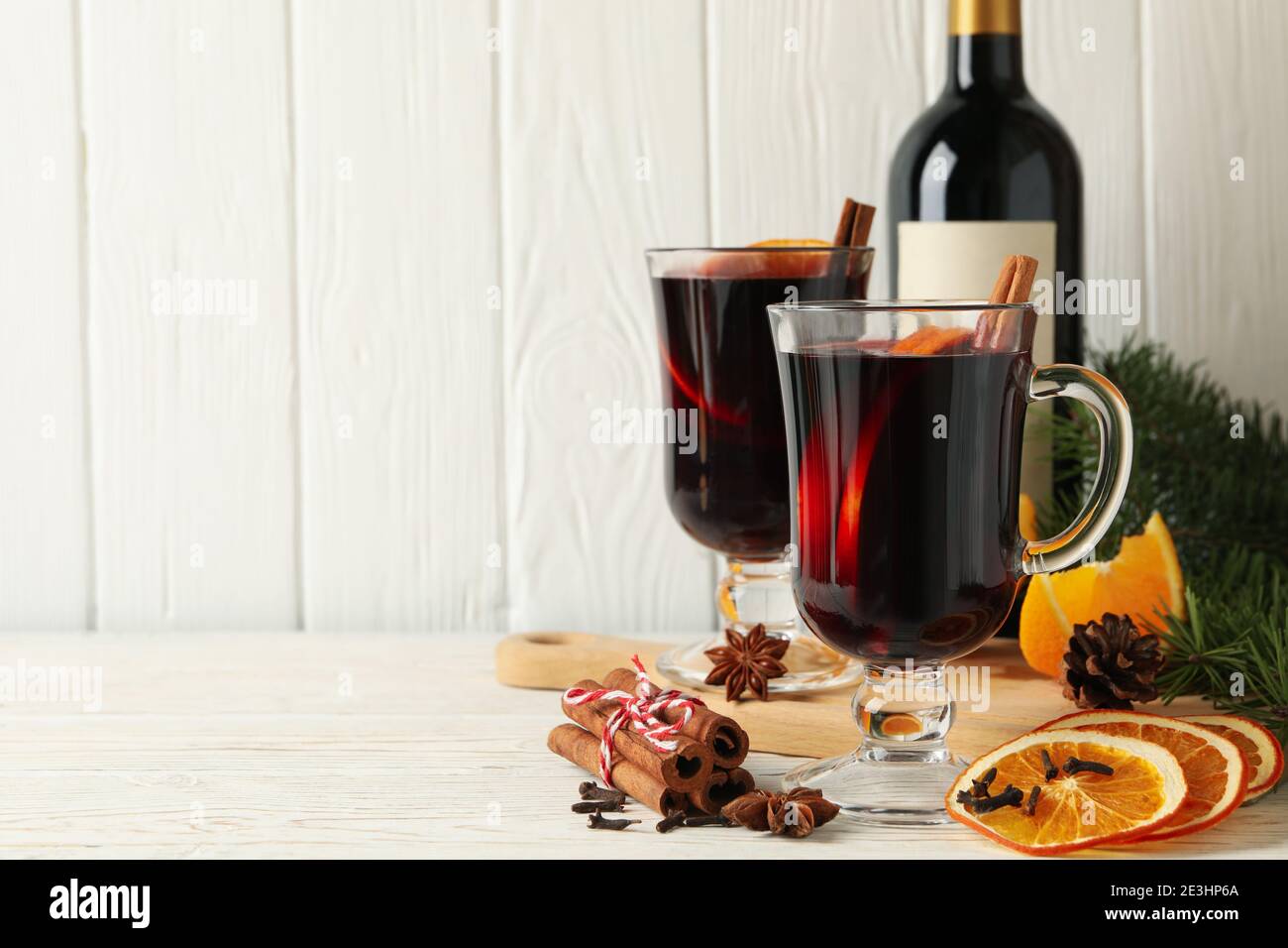Flasche Wein und Tassen mit Glühwein mit Gewürzen auf Holz, Zutaten für Glühwein in einer rustikalen Winterszene Stockfoto
