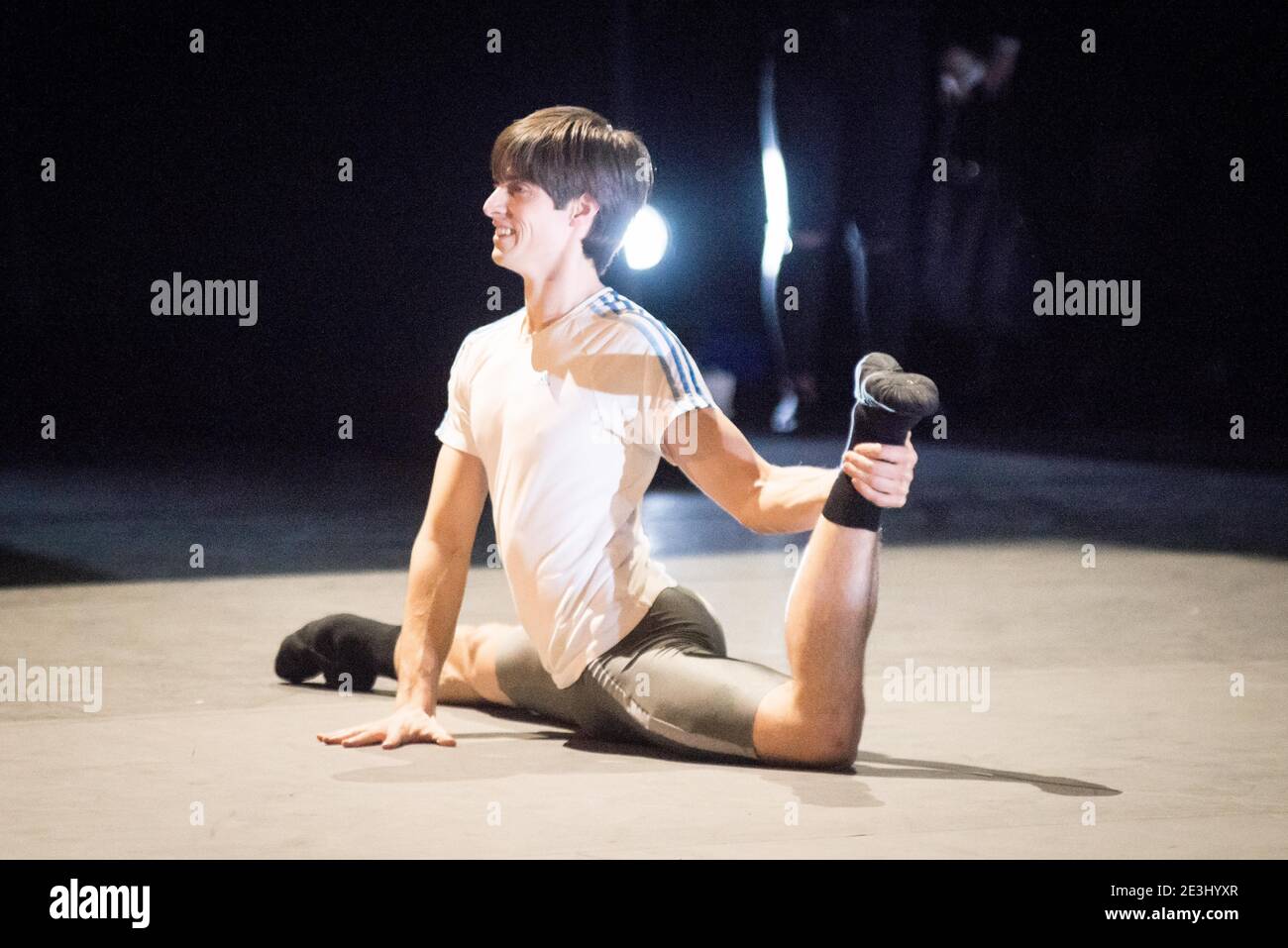 Der männliche Balletttänzer Xander Parish posiert in flexibler Ballettpose auf dem Boden der Bühne Stockfoto