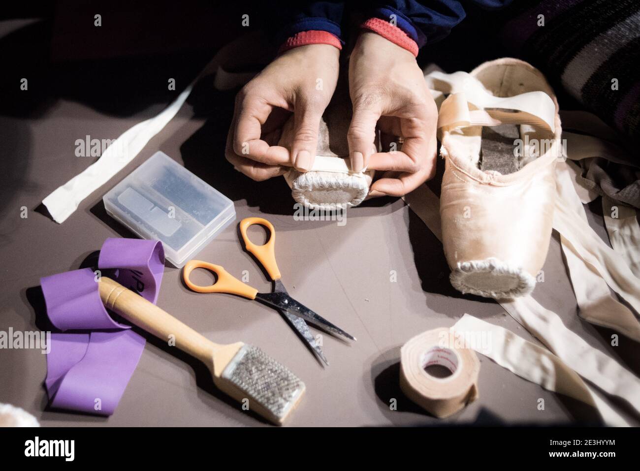 Nahaufnahme der Ballerina, die ihre spitzenschuhe mit Klebeband, Scheren und Bändern vorbereitete. Werkzeuge des Balletthandels Stockfoto