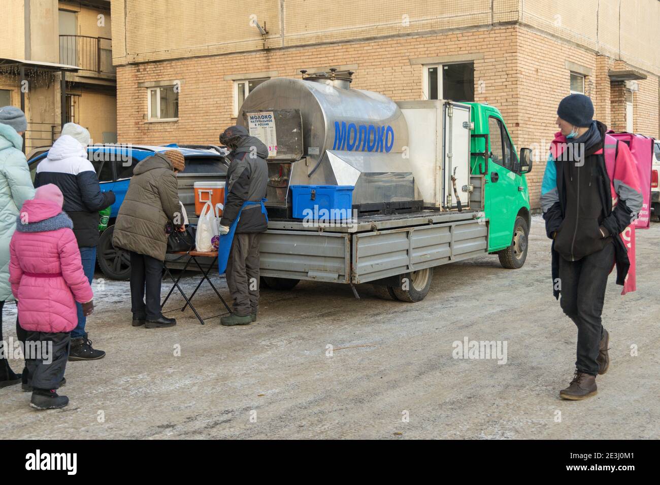 Sankt Petersburg, Russland - 09. Januar 2021: Verkäufer und Käufer von Bauernmilch in der Linie in der Nähe des Tanks mit der Inschrift auf Russisch 'Milch' Stockfoto