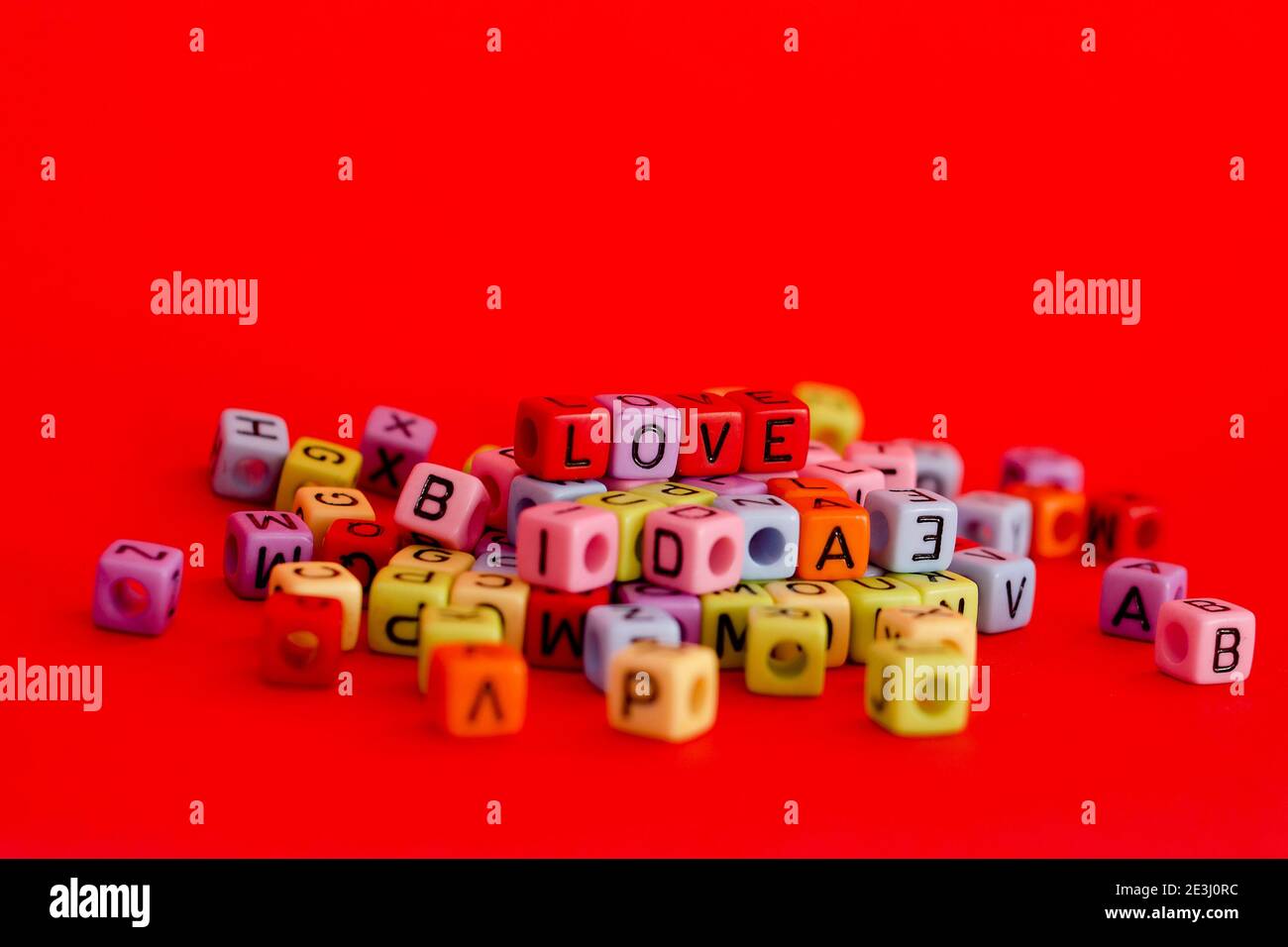 Bunte Holzwürfelperlen mit Buchstaben auf rotem festlichem Hintergrund, Wort "Liebe". Valentinstag. 14 Februar. Flach liegend, Draufsicht. Stockfoto