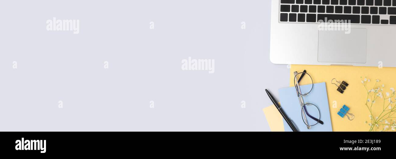Banner mit Laptop, Blumen und Bürobedarf auf blauem und goldenem Hintergrund. Femininer Arbeitsplatz. E-Learning, Fernarbeitskonzept mit Kopierraum. Stockfoto