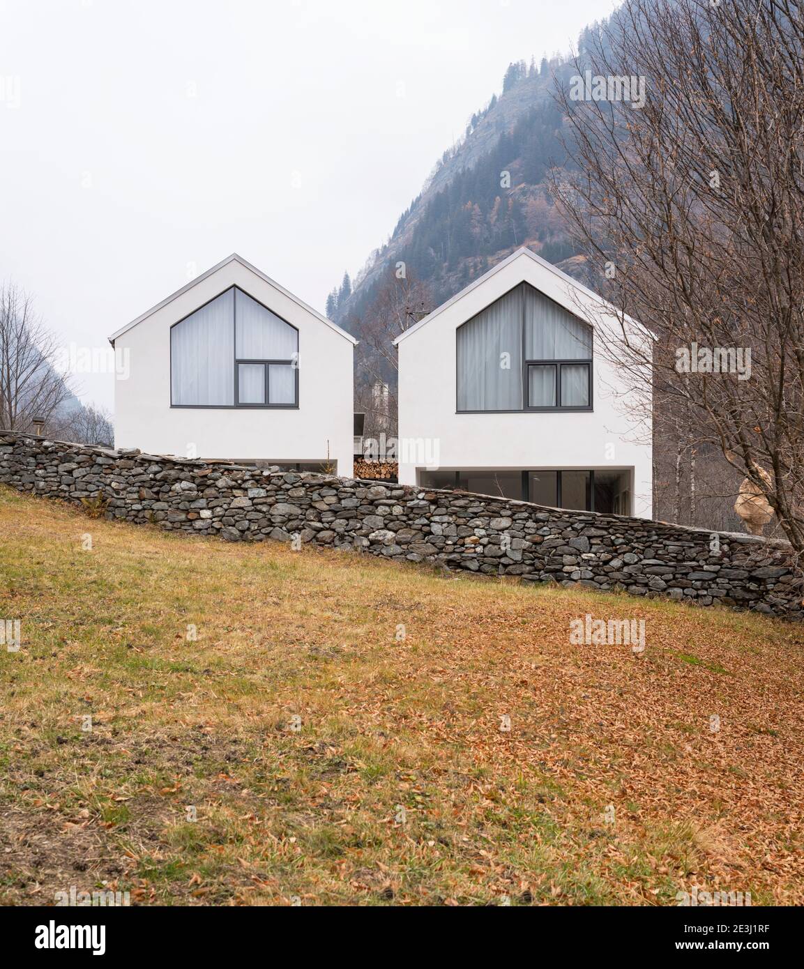Weißes Haus umgeben von Natur, Wald und Nebel im Winter. Gebäude im schweizer Tal. Niemand drinnen Stockfoto