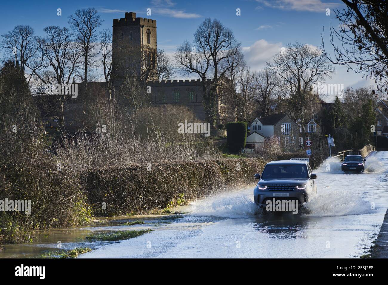 Autos, die durch Oberflächenwasser auf überschwemmten Straßen an der Felmersham Bridge, Bedfordshire, England, Großbritannien planschen Stockfoto