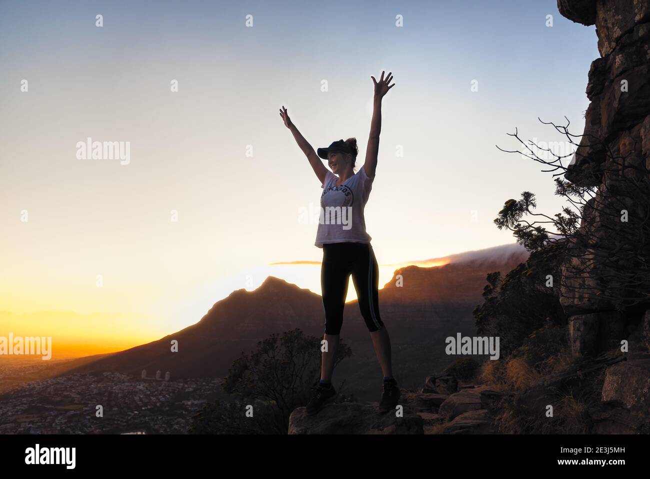 Ein junges Mädchen erreicht den Himmel in Freude zu feiern Ankunft auf der Spitze eines Berges nach einer malerischen Wanderung bei Sonnenaufgang. Stockfoto