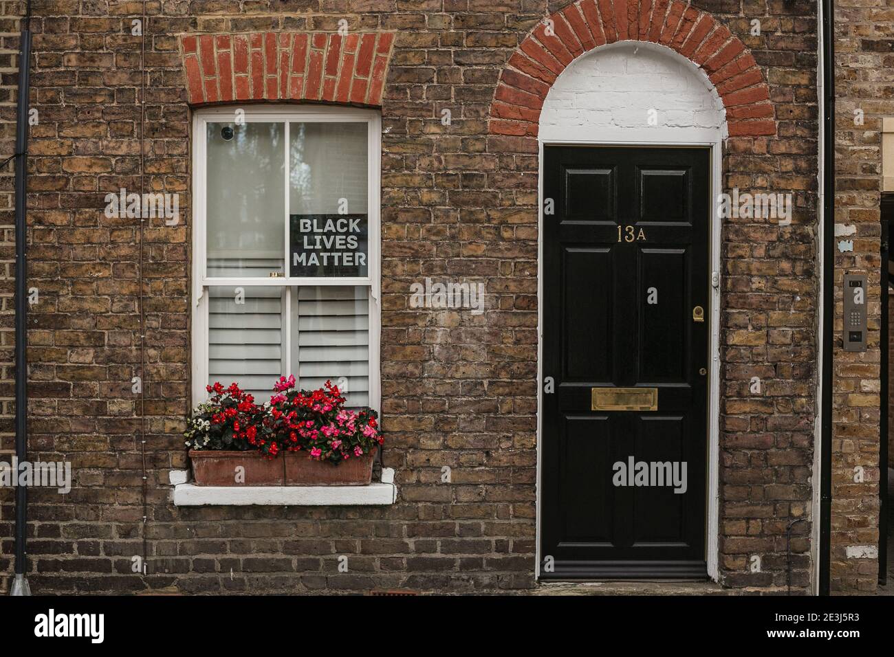 Hauseingang mit einer schwarzen Tür und einem Black Lives Matter Schild am Fenster. Einige Straße in Windsor, Berkshire, England, Großbritannien. Stockfoto