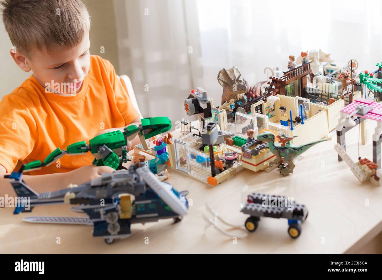 SAINT-PETERSBURG, RUSSLAND - NOVEMBER 26, 2020 Junge spielen mit lego-Steinen sitzen am Schreibtisch, Welt der Dinosaurier von Kind gebaut Stockfoto