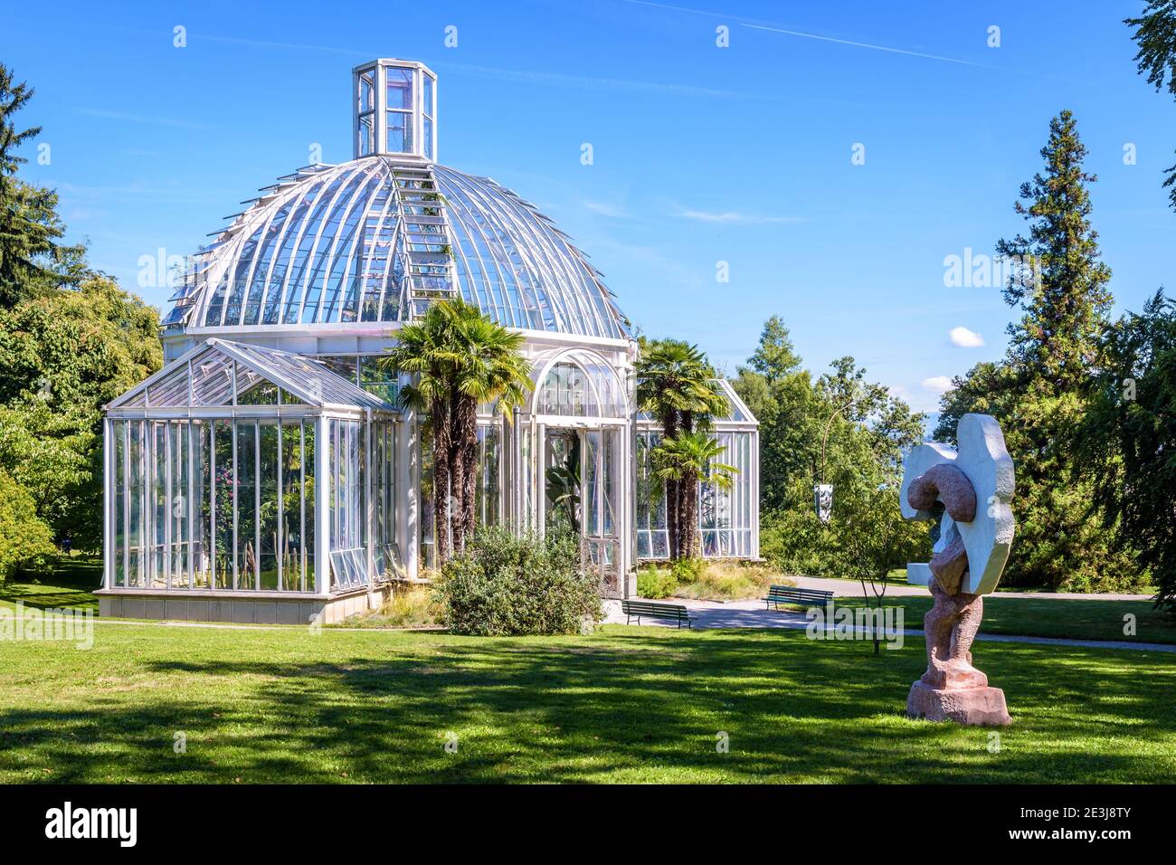 Das gemäßigte Gewächshaus im Konservatorium und Botanischen Garten von Genf und die Skulptur 'Portatore di zucche'. Stockfoto