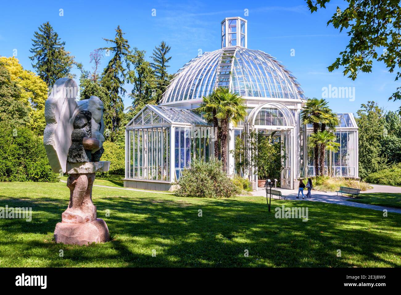 Das gemäßigte Gewächshaus im Konservatorium und Botanischen Garten von Genf und die Skulptur 'Portatore di zucche'. Stockfoto