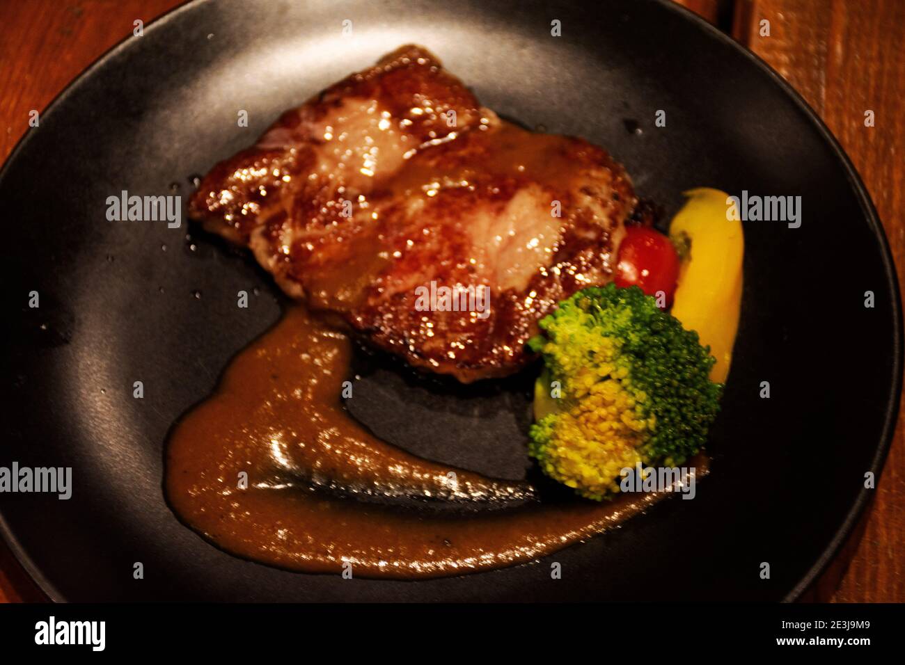 Medium seltene Steak Rindfleisch Zunge Belag Soße serviert Mit gegrilltem Gemüsesalat in Keramikplatte im Café Cafe-Bar und Restaurant im Hotel Stockfoto