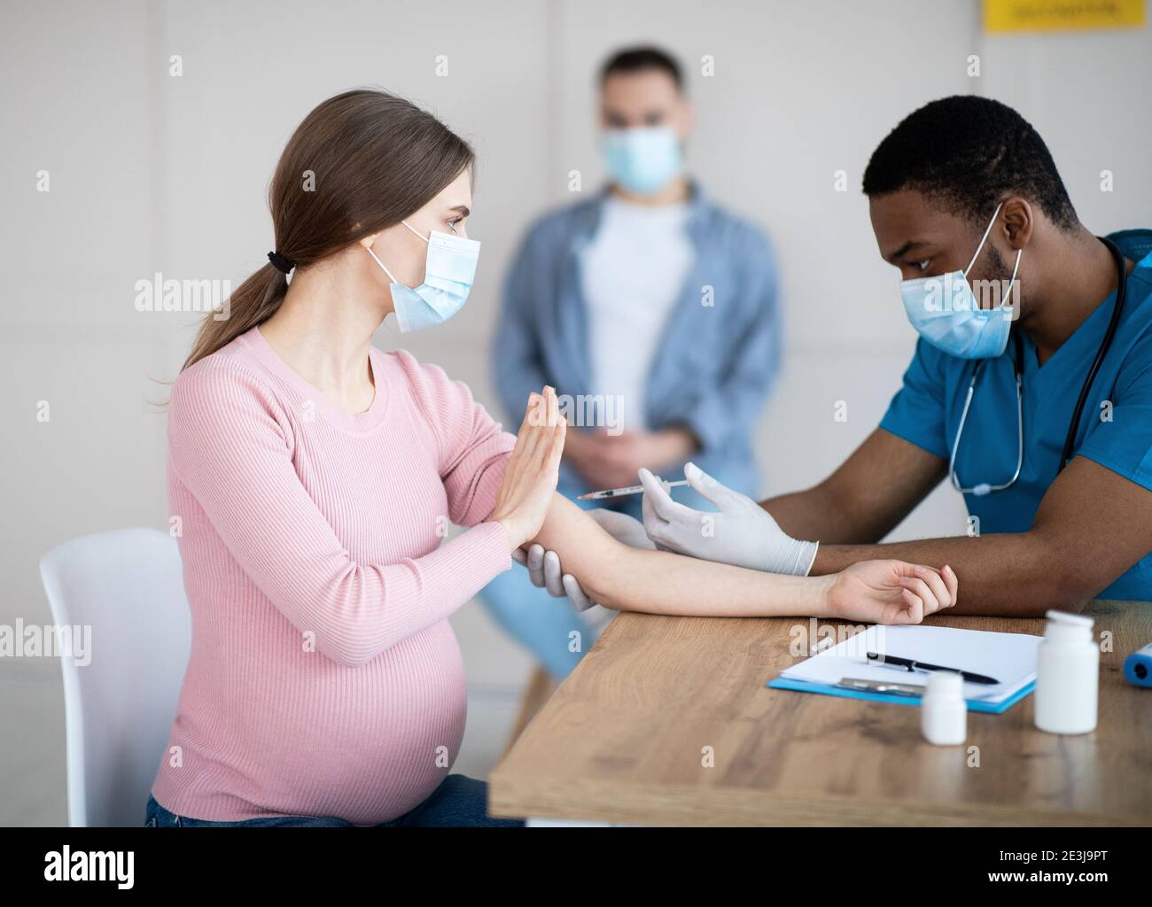 Schwangere Dame, die den Arzt davon abhält, einen covid-19-Impfstoffschuss zu machen, um die Coronavirus-Immunisierung in der Klinik zu bekämpfen Stockfoto