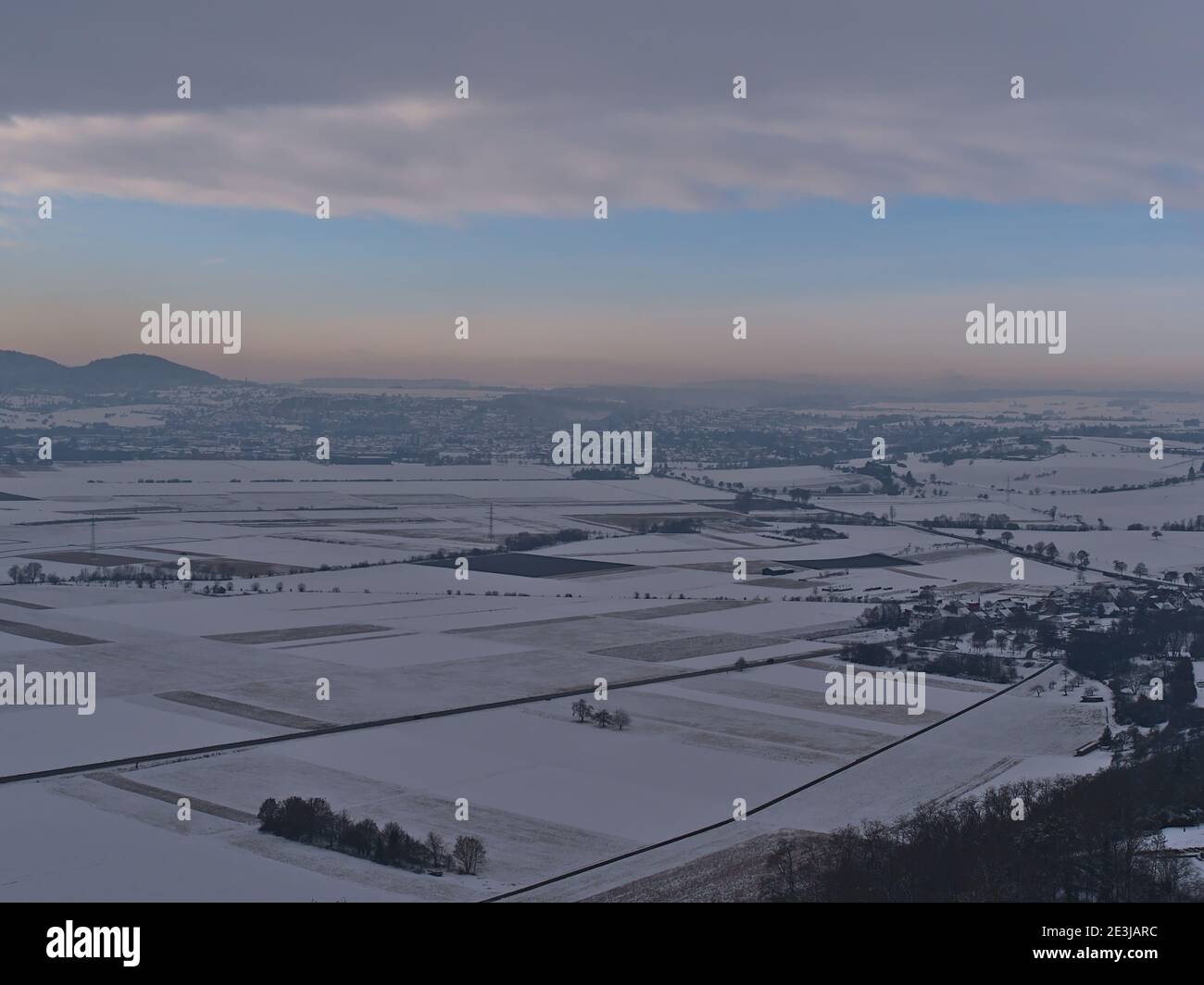 Schöne Luftaufnahme der Winterlandschaft mit Tal von schneebedeckten strukturierten landwirtschaftlichen Feldern, Landstraße und Stadt Rottenburg am Neckar, Deutschland. Stockfoto