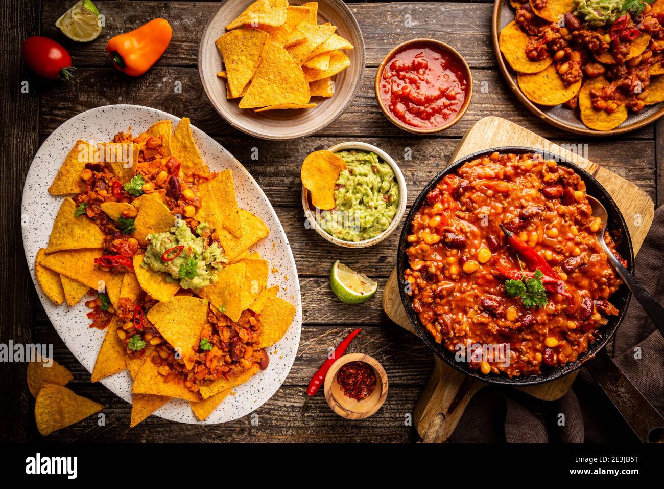 Mexikanisches Food-Konzept: Tortilla Chips, Guacamole, Salsa, Chili con Carne und frische Zutaten auf Holzhintergrund, Draufsicht Stockfoto
