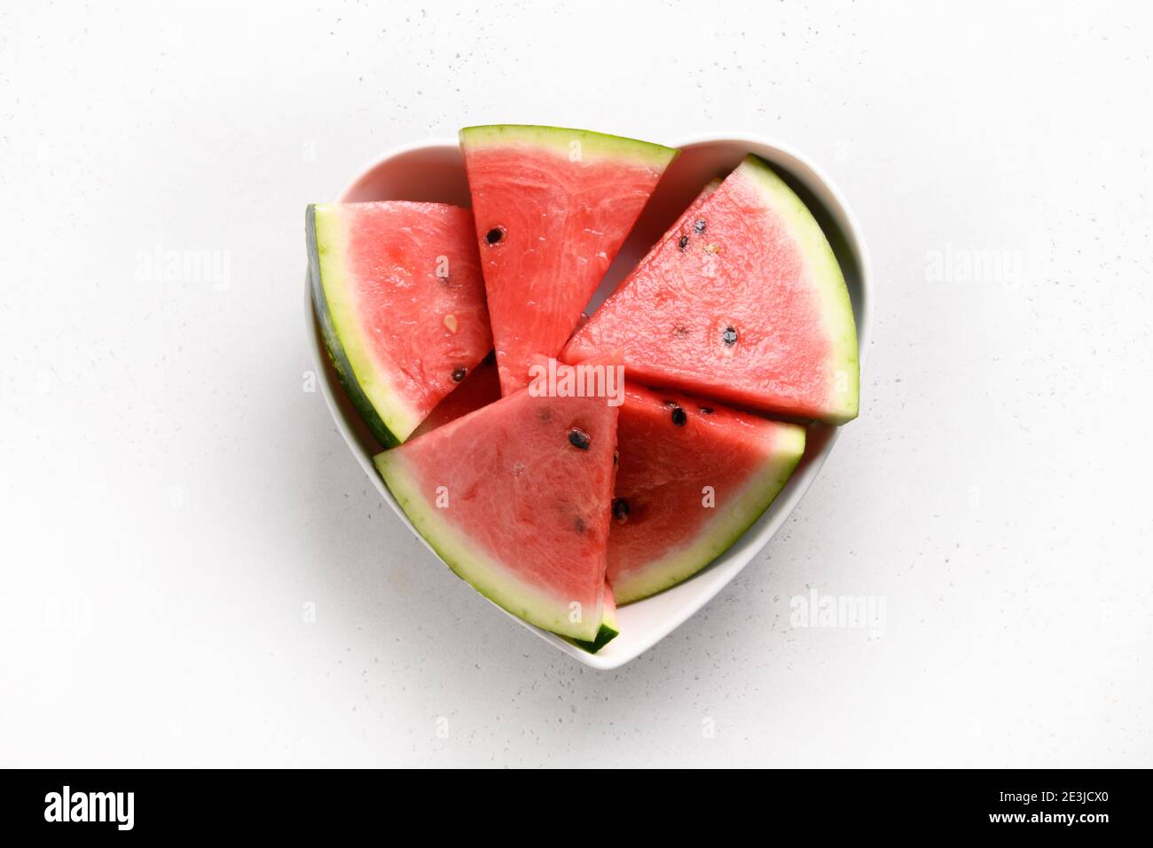 Wassermelone Scheiben in Teller als Herz auf weißem Hintergrund. Flach liegend. Leckeres Dessertessen. Stockfoto