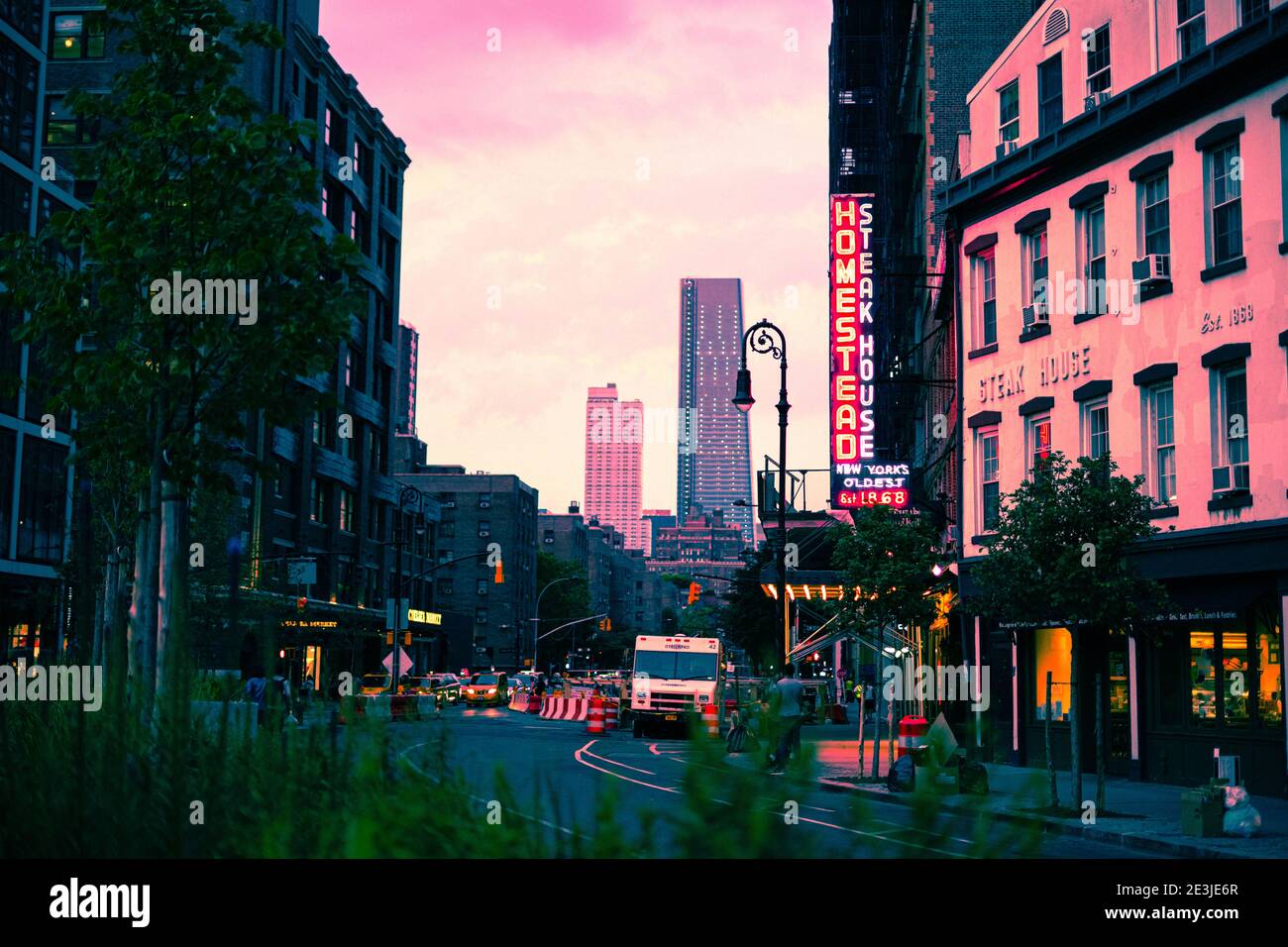 Sonnenuntergang an der 9. Ave. Old Homestead Steakhouse ist auf der rechten Seite zu sehen und 1 Manhattan West ist auf dem Hintergrund. Bäume im Vordergrund. Stockfoto