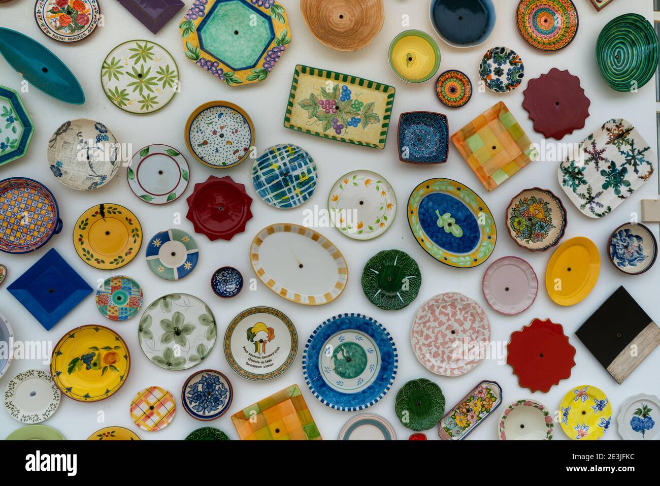 Viele verschiedene und bunte Teller und Schüsseln hängen an der Wand Stockfoto