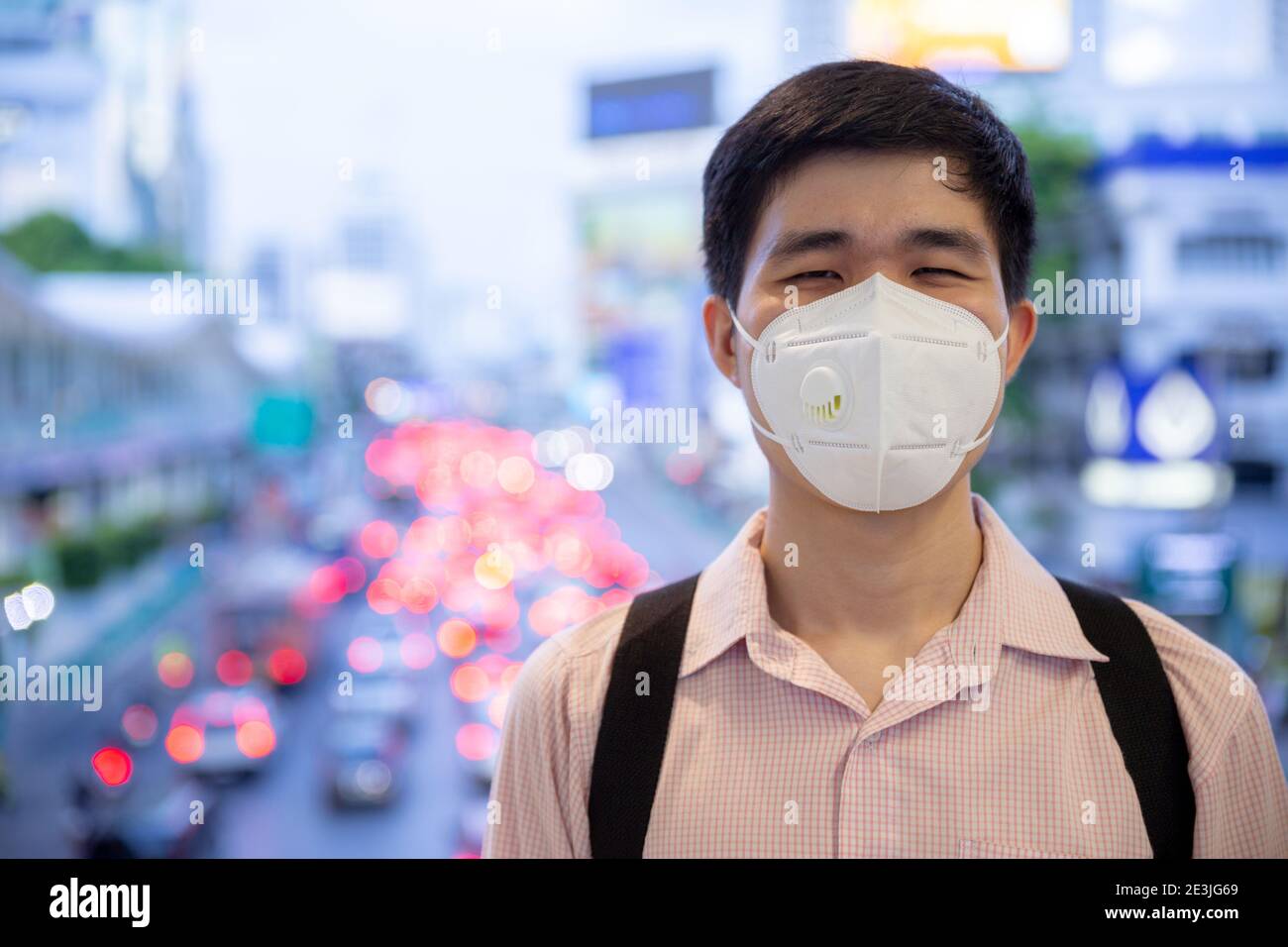 Asian Mann lächelnd hinter medizinischen Schutzmaske in neuen normalen Lifestyle-Konzept. Stockfoto