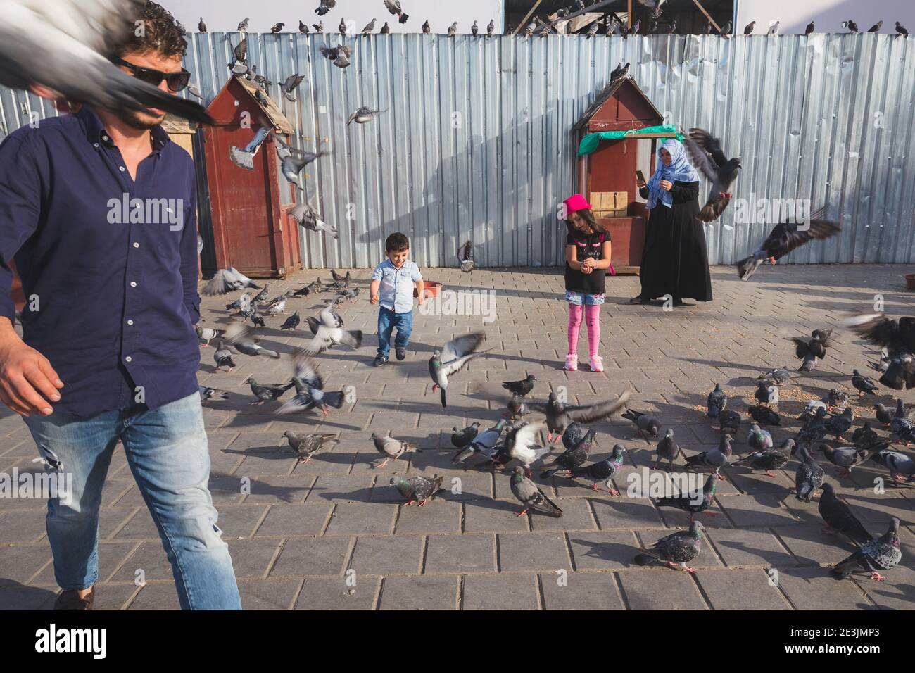 Istanbul, Türkei - 18. September: Junge türkische Kinder laufen auf den Straßen Istanbuls unter einer chaotischen Schar von Stadttauben. Stockfoto