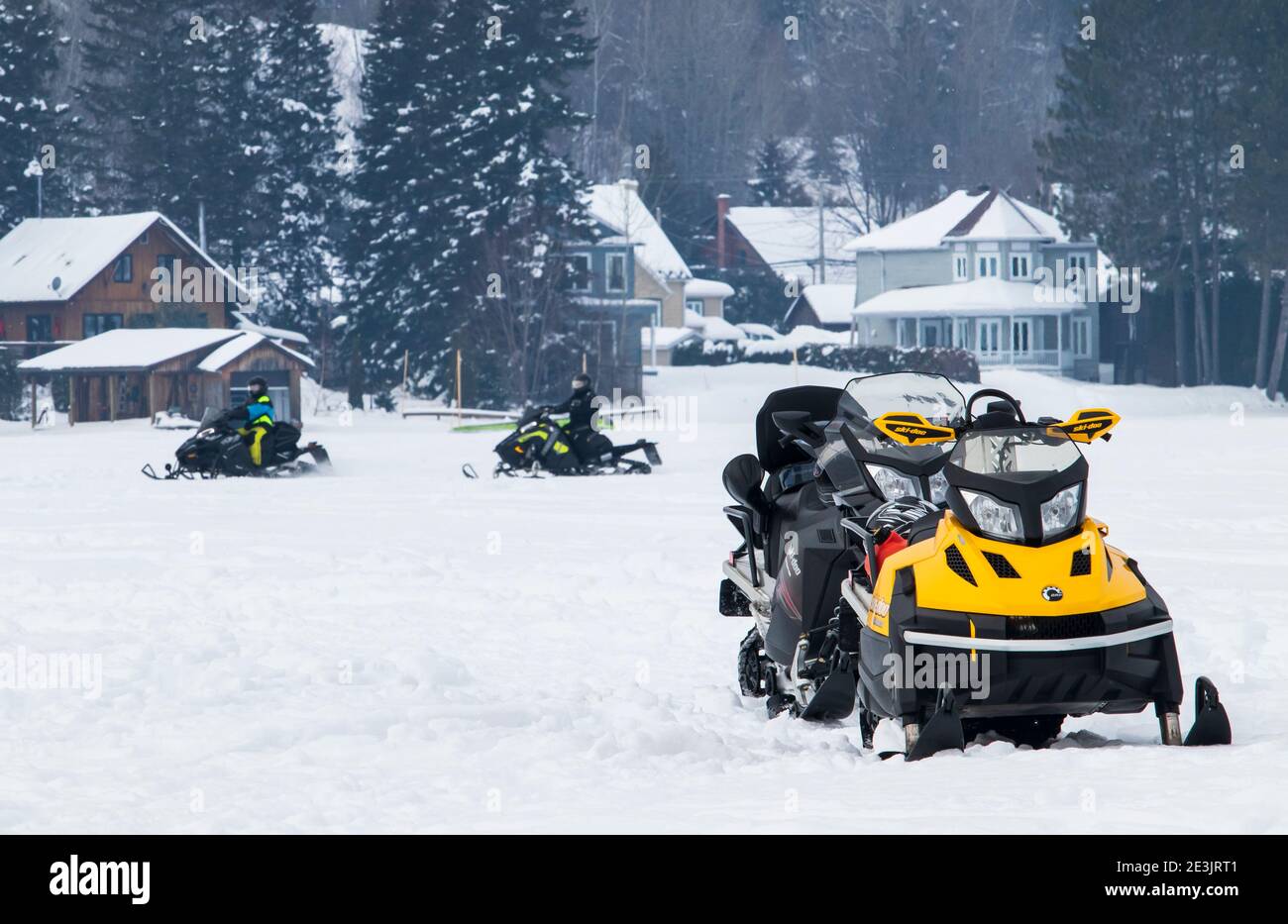 Februar 2, 2020 - Saint-Jean-des-Piles, QC; Kanada: Zwei leere Schneemobile auf einem gefrorenen See und zwei Schneemobile im Hintergrund geparkt Stockfoto