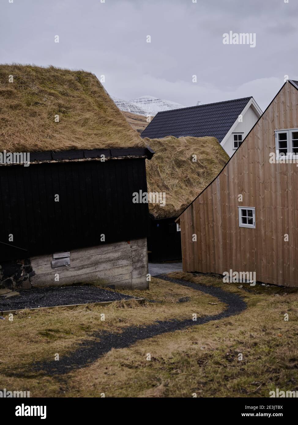 Schotterweg, der zu reetgedeckten Dachhäusern in der Färöer führt Inseln Stockfoto