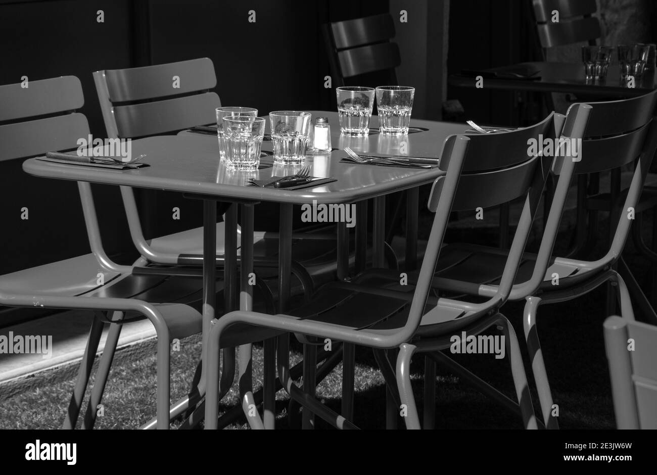 Leerer Café-Terrassenbereich zum Mittagessen. Niemand. Zurückgelassener Lebensstil. Unmögliche Dinner-Party, Wirtschaftskrisenkonzepte. Schwarzweißfoto Stockfoto