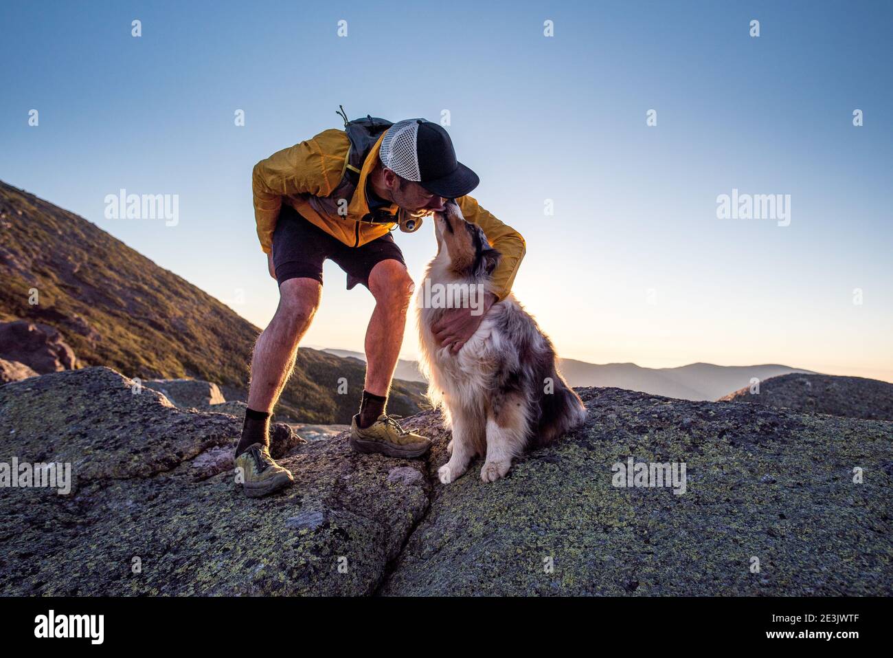 Hund lecken ownerâ €™s Gesicht während Trail läuft in den Bergen Stockfoto