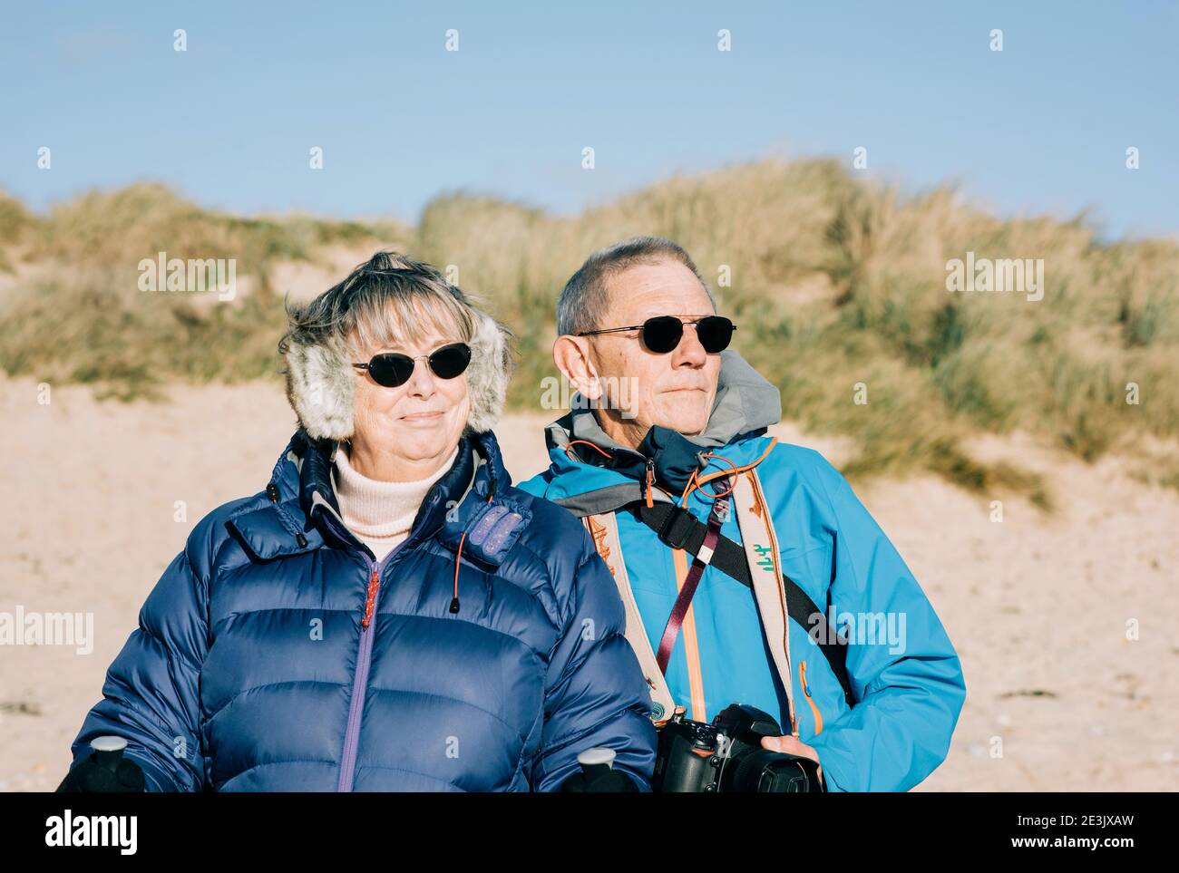 Ein Paar mit 70s Jahren stand am Strand mit Blick auf den Strand Zum Meer Stockfoto